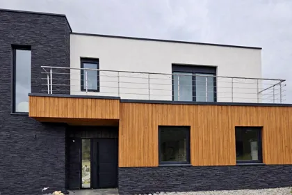 Modernes Einfamilienhaus mit dunkler Natursteinverkleidung und Holzfassade – Projekt von CHRISBAU